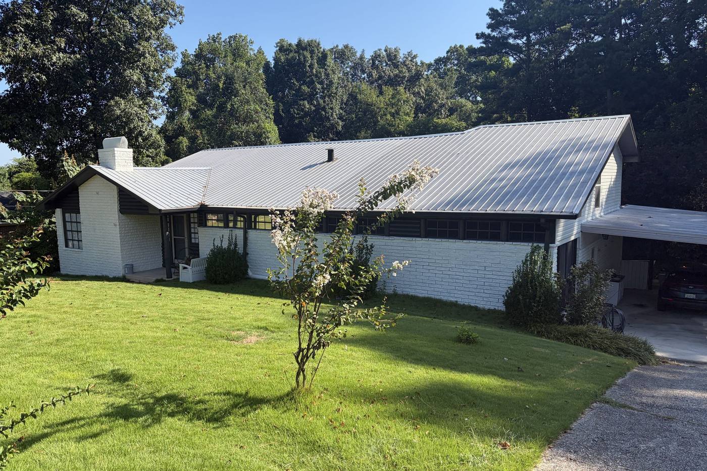 Front of the house after renovation: freshly painted white brick, dark trim, and a tidy lawn