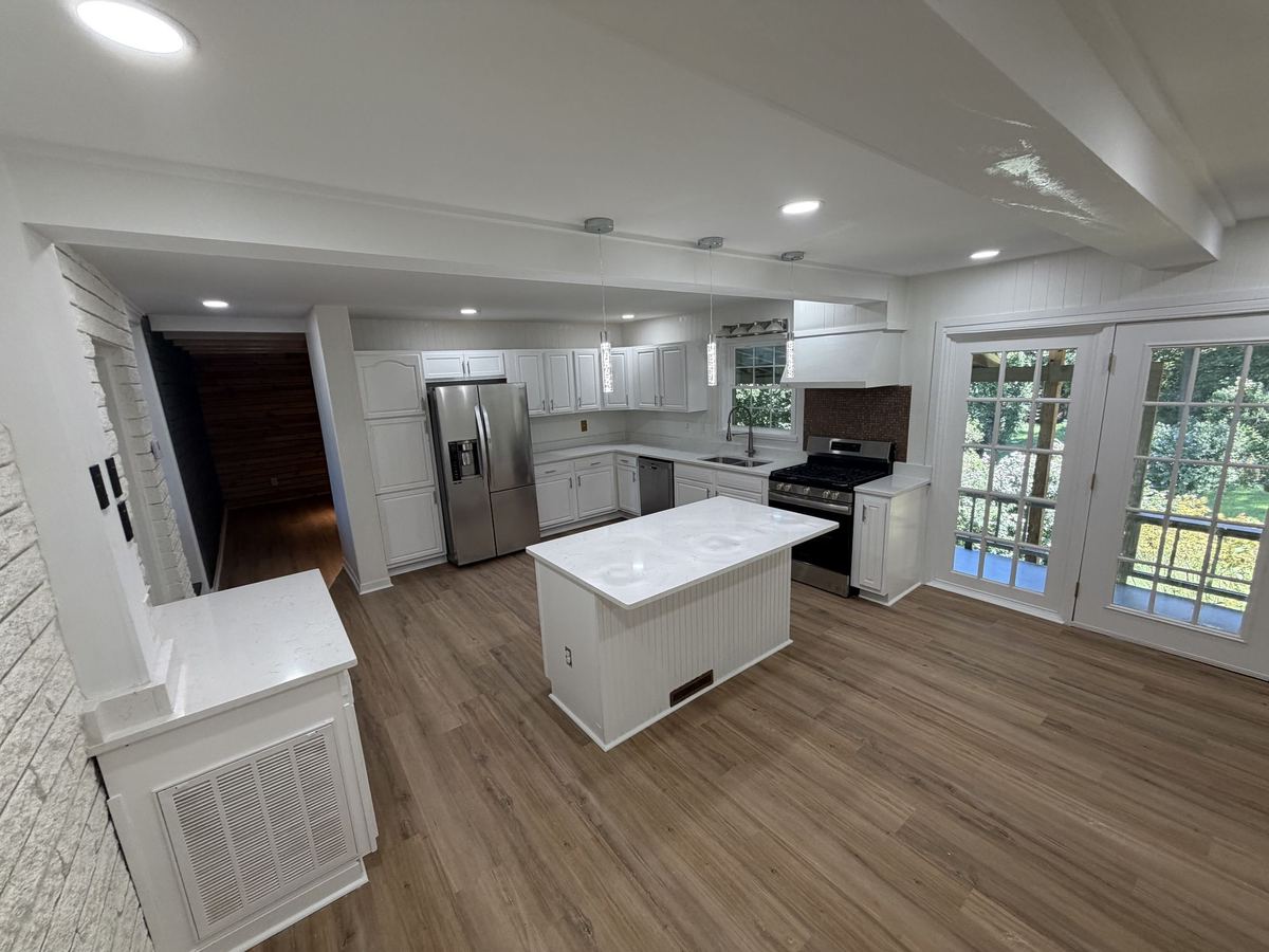 Open kitchen and dining area with white cabinets, a white island, and French doors